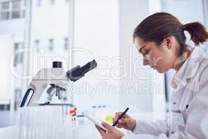 Research is only one part of the job. Shot of a focused young female scientist working on a digital tablet while being seated inside of a laboratory.