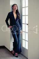 Timelessly elegant. Shot of a beautiful woman wearing a classic feminine suit posing alongside french doors.