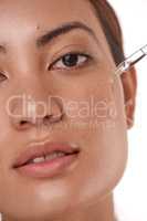 A little goes a long way. Shot of a beautiful young woman posing with a serum dropper against her face.