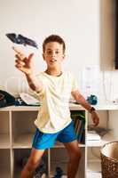 Letting his imagination soar. Portrait of a little boy flying a paper jet at home.
