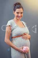 Saving up for baby. Cropped shot of a pregnant woman holding a piggybank against a gray background.