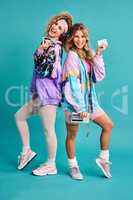 Were out spreading some 80s vibes. Studio shot of two beautiful young women styled in 80s clothing.