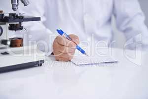 Recording his observations. A cropped shot of a scientist recording observations on a piece of paper while sitting in his lab.