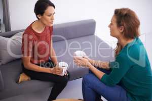 Quick coffee discussion. Shot of two female professionals having a discussion in an informal office setting.