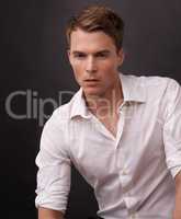 Handsome and reserved. A handsome young man in a white shirt against a black background.