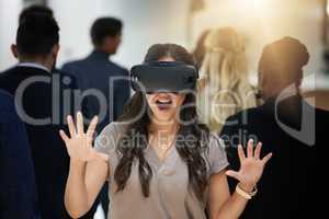 Who knows what youll discover. Shot of a young businesswoman wearing a VR headset in a busy office.