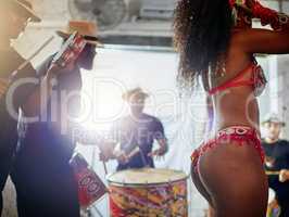 Where does these moves come from. Low angle shot of an unrecognizable woman wearing festive clothing while dancing to music played by a band inside of a club at night.