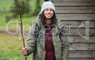 Im ready to catch my own dinner. Portrait of a happy young man standing outside with his fishing rod in his hand.