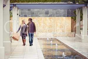 Today is date day. An affectionate young couple walking under a pergola next to a water feature.