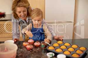 Cake Boss at work. A little girl decorating cupcakes with the help of her grandmother.
