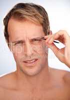 How do women do this. Cropped studio shot of a man wincing in pain while plucking his eyebrows.