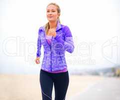 Getting fitter by the step. Shot of a young woman in sportswear standing at the beach.