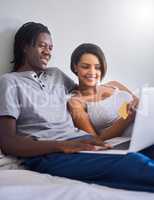 Spoil her in the bedroom. Shot of a young couple doing some online shopping with a credit card.