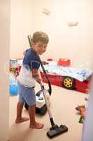 Keen to clean. Shot of a little boy vacuuming his bedroom at home.