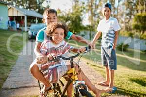 First rule of brotherhood Ride a bike together. Shot of happy young brothers riding a bicycle together in their backyard.