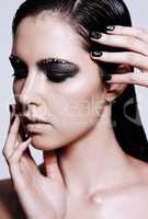 Metallic beauty. Studio shot of a beautiful young woman wearing metallic-colored makeup and nail polish.