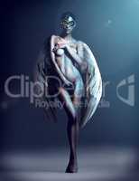 Dangerously desirable. Studio shot of a naked woman with wings and a mask.