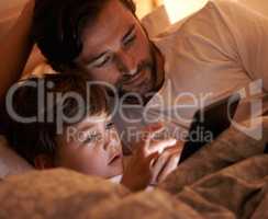 Digital story time. A father and son lying in bed with an e-reader.