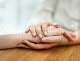 Offering support and comfort. Shot of two people holding hands in comfort.
