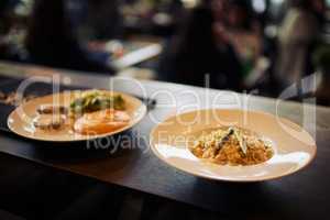 The food here always looks on point. Shot of two plates of food standing on a counter and ready to be taken out to customers inside of a restaurant during the day.