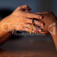 Finding comfort in religion. Closeup shot of a two people holding hands in support with a rosary.