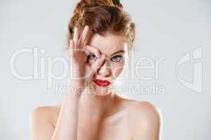 Playful beauty. Studio shot of a beautiful young woman pouting while looking at the camera through her fingers.