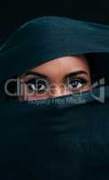 Modesty is the new sexy. Cropped shot of an attractive young woman wearing a hijab and only exposing her eyes while against a black background.