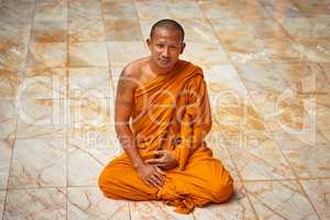 Sitting in quiet meditation. Portrait of a buddhist monk sitting on a monastary floor.