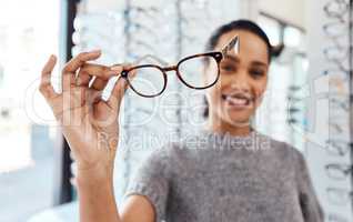 Raise your glasses to good eye health. Shot of a young woman buying a new pair of glasses at an optometrist store.