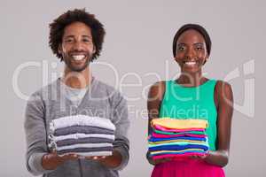 Gender equality. Studio shot of a young man and woman each holding a neatly folded pile of clothes.