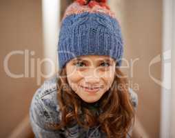 Time for some vacation fun. Shot of a young girl posing in her woolen hat indoors.