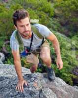 Heading in the right direction. Shot of a handsome young man scaling a mountain.