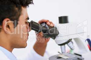 Looking for solutions in the microscopic world. Shot of a lab technician using a microscope while sitting in a lab.