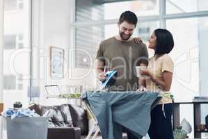 Dividing the chores is the simplest way to domestic bliss. Shot of a happy young couple ironing freshly washed laundry together at home.