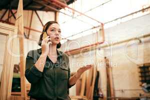 Im always gettin new orders. Shot of a female carpenter talking on her cellphone while standing in her workshop.