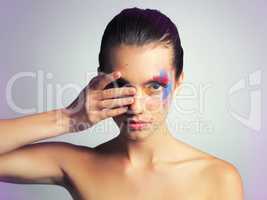 Wear war paint and keep your eye on the prize. Studio shot of an attractive young woman posing with her face brightly painted.