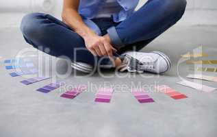 Purple for posperity. Shot of a female sitting crossed legged chosing paint colours.