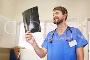 If you can identify it, you can treat it. Shot of a young doctor analyzing an x-ray alone in his office.