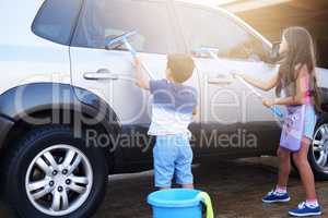 Cleaning up is everyones responsibility. Shot of a little boy and his sister washing a car at home.