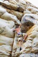 Getting to the top. A rock climber climbing up a cliff face.