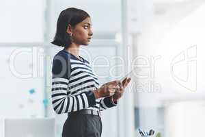 Focus and discipline govern how far you get in life. Shot of a young businesswoman holding a digital tablet and looking out the window in her office.