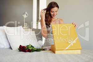 Shes never going to forget this anniversary. Shot of a young woman opening a surprise gift at home.
