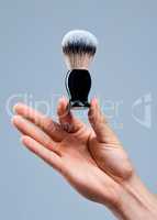 Even application. Shot of an unrecognizable man holding a brush against a grey background.