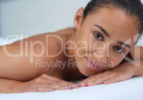 I am in my element. Portrait of a beautiful young woman relaxing on a massage table at a spa.