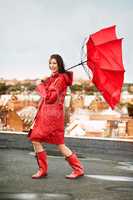 Facing the storm with a smile. Young woman laughing while being battered by rain and wind on a rooftop.