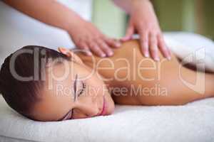 Letting her worries drift away. Shot of a young woman enjoying a back massage at a spa.