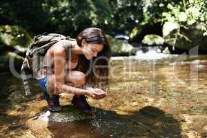 Freshening up in the forest. A young woman stopping for a water break while out hiking in the forest.