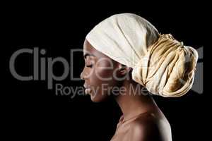 The profile of beauty. Studio shot of a beautiful woman wearing a headscarf against a black background.