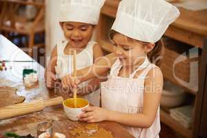 Baking is so much fun. Two little girls having fun while baking in the kitchen.
