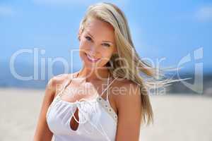 She makes the beach even more inviting. Shot of a happy young woman smiling while on the beach.